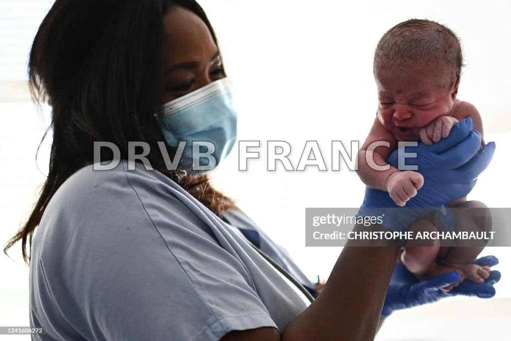 A nurse holds a new-born baby moments after her birth at the... News ...